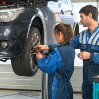 Mechanic teaching an intern the best practice. Learning on the job during a practical internship in a garage