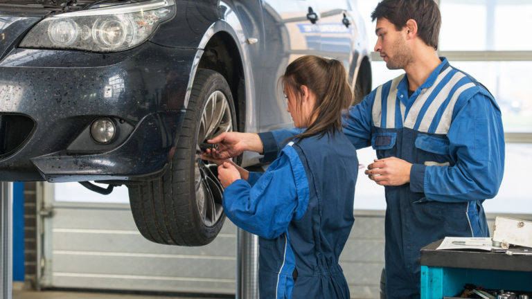 Mechanic teaching an intern the best practice. Learning on the job during a practical internship in a garage